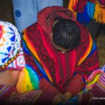 Man in red poncho and Andean priest