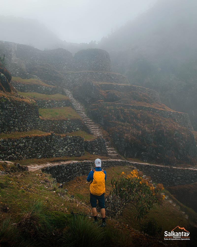 Tourist with an orange-coloured mohair at an archaeological site on the Inca Trail lost in a vast mist