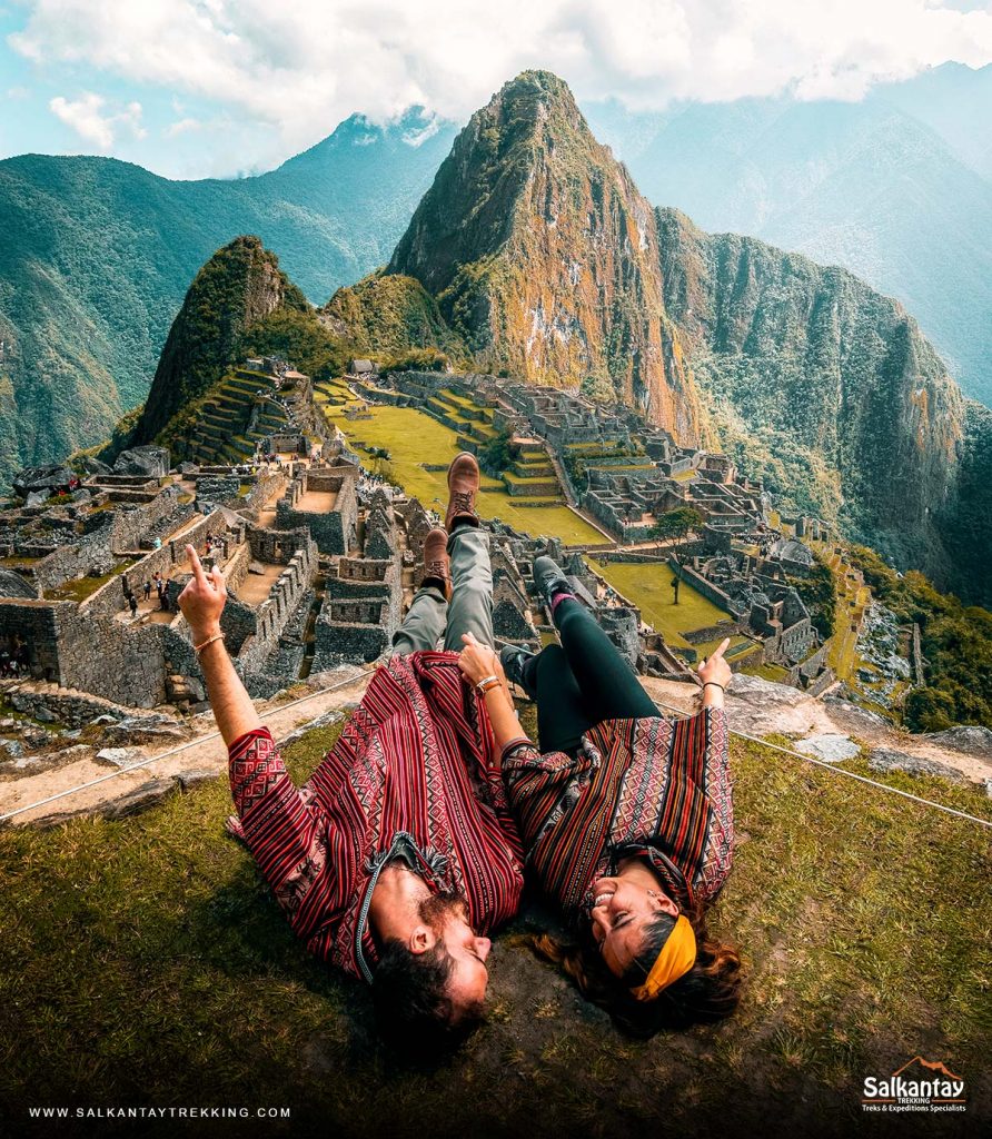 Two tourists wearing Andean ponchos in front of the Inca citadel of Machu Picchu.