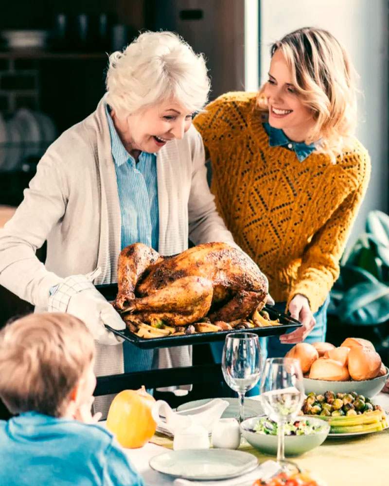 a grandma holding the roast turkey at the thanksgiving day dinner