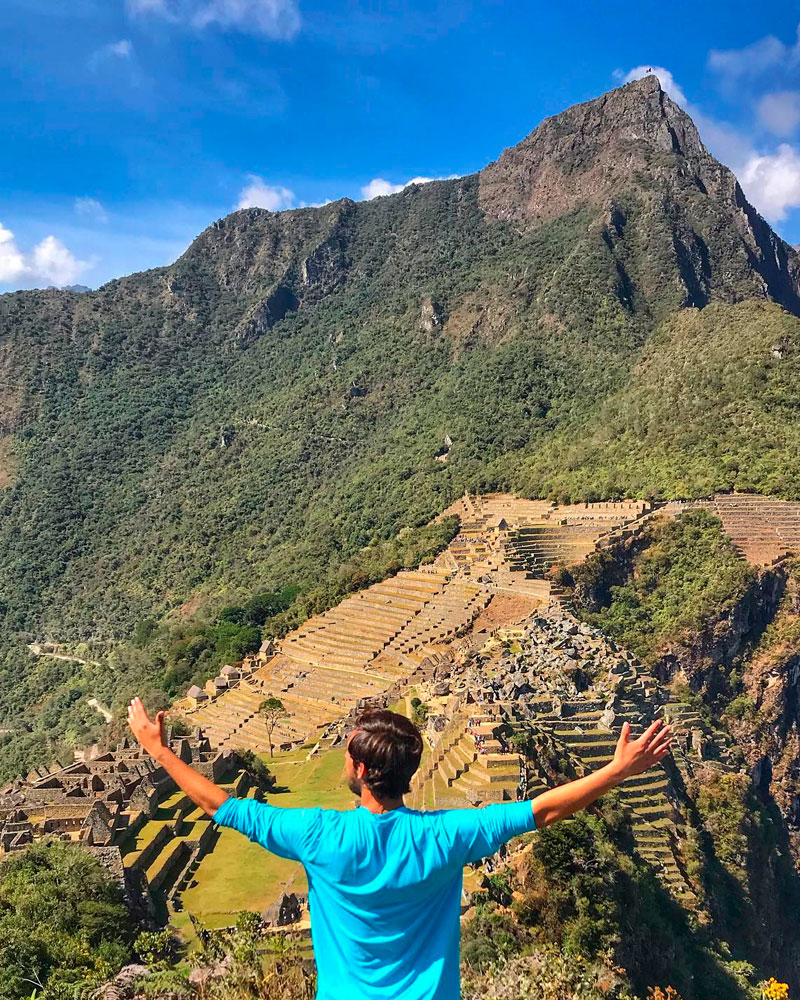 man standing in the top of huchuy picchu mountain