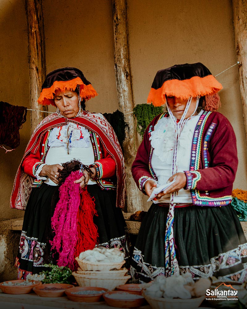 Two Andean women weaving and explaining the weaving process.