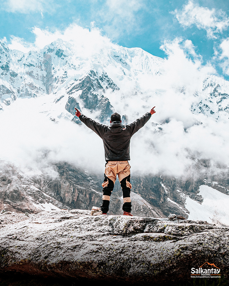 Tourist in the Salkantay pass raising his hands and the bottom of the Salkantay mountain.