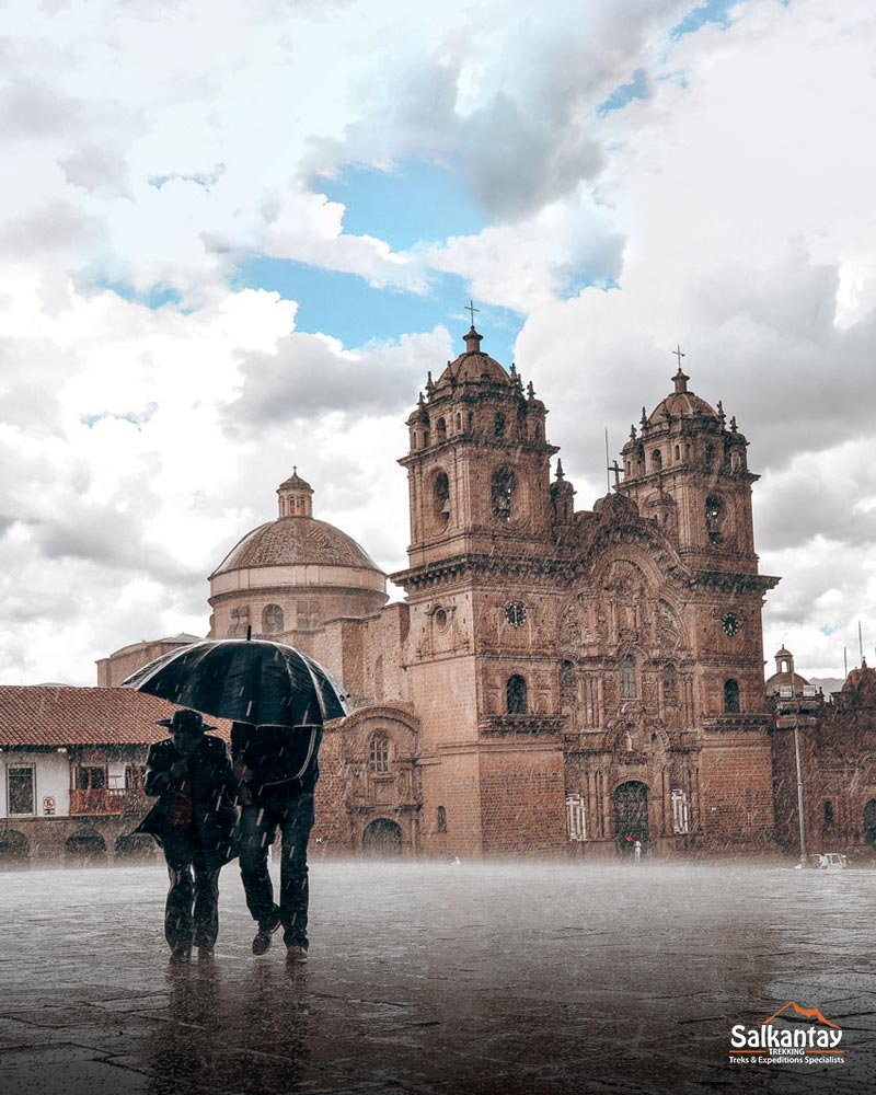 Two tourists with umbrellas in Cusco's main square in the pouring rain