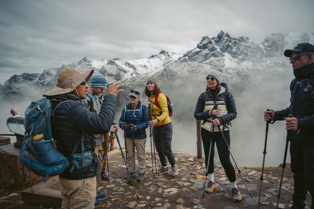 A group of tourists with trekking poles and their guide getting ready to start the hike to Vinicunca, the “Mountain of Colors”