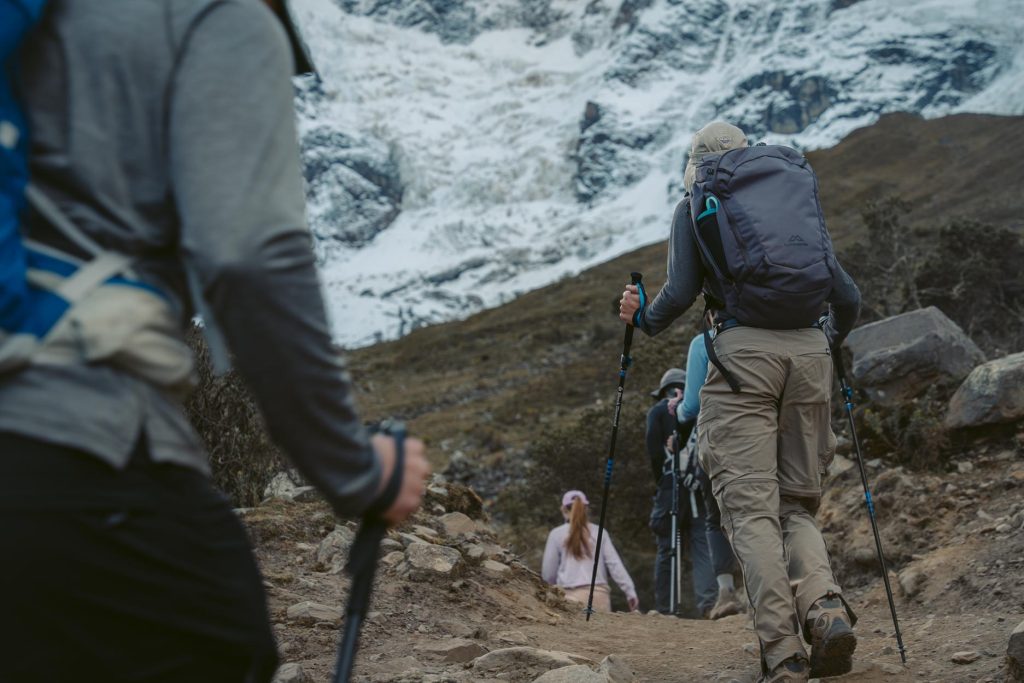 A group of tourists hiking the Salkantay Trail with proper trekking poles.