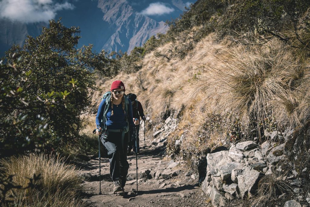 Woman walking with trekking poles through the Inca Trail to Machu Picchu