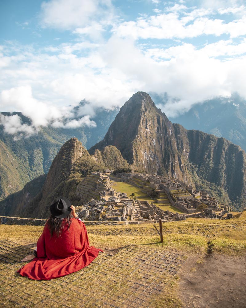 Tourist with red Andean poncho in Machu Picchu citadel