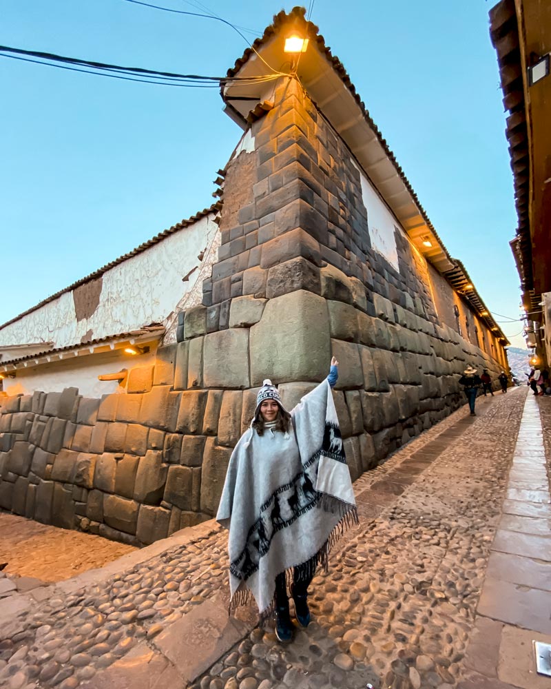Tourist with Andean poncho at the 12-angle stone