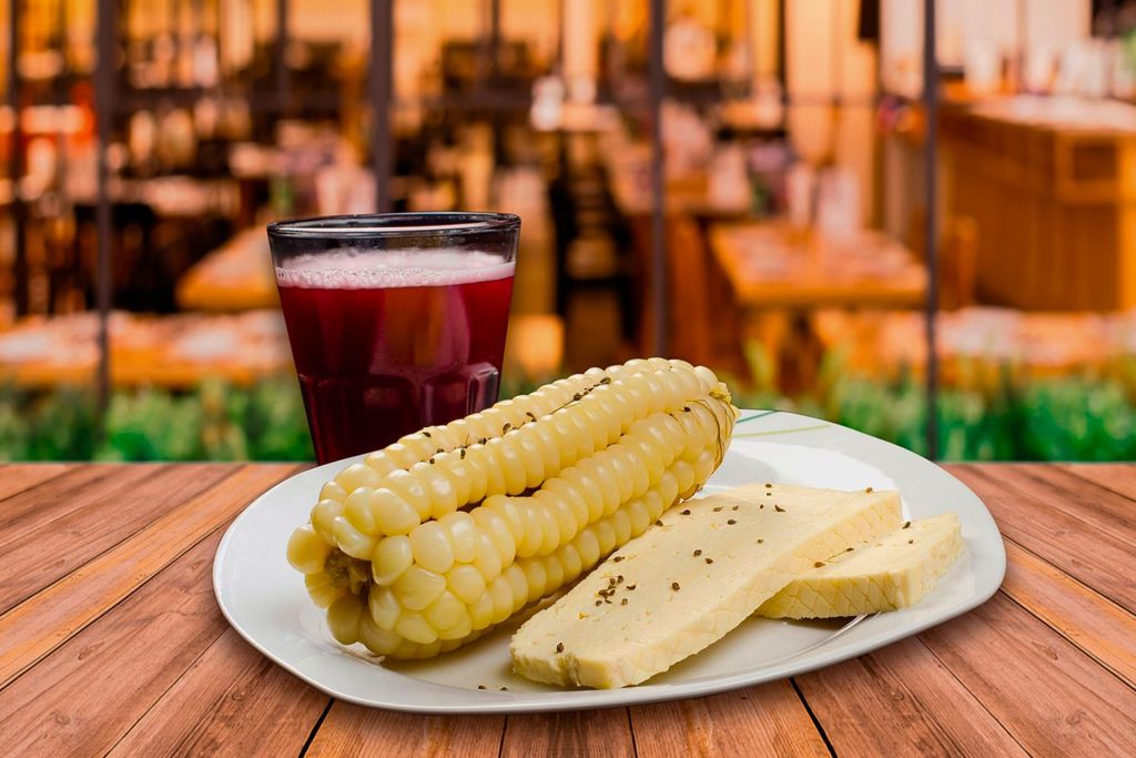 Corn with cheese, alongside a glass of purple chicha