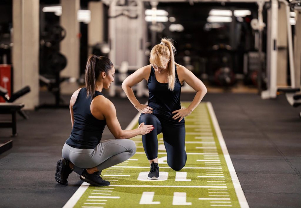 Photo of a woman starting at the gym with a coach