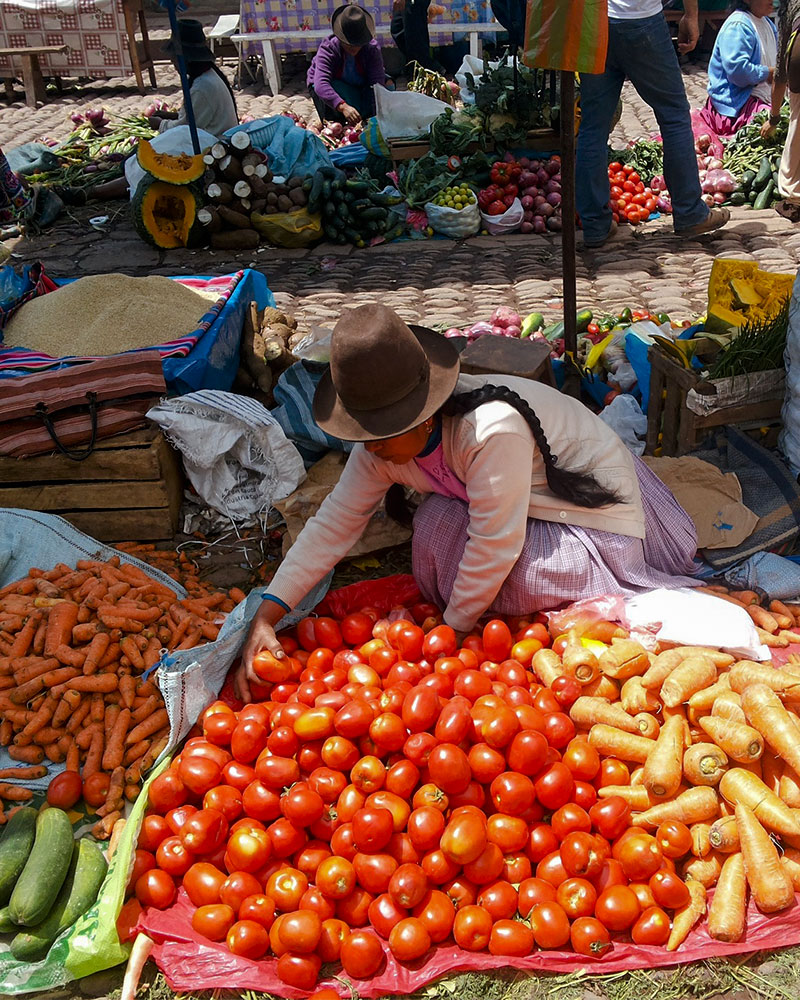 Woman selling tomatoes and carrots at a market in Cusco
