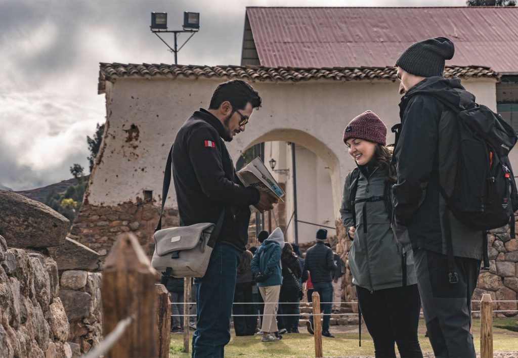 Couple of tourists with their guide touring the archaeological complex of Chinchero