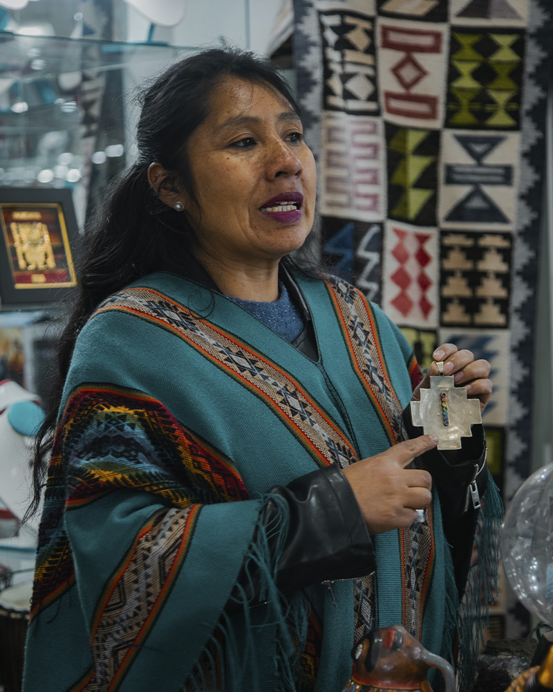 Woman at a shop selling silver jewelry explaining how they make their art in Pisac