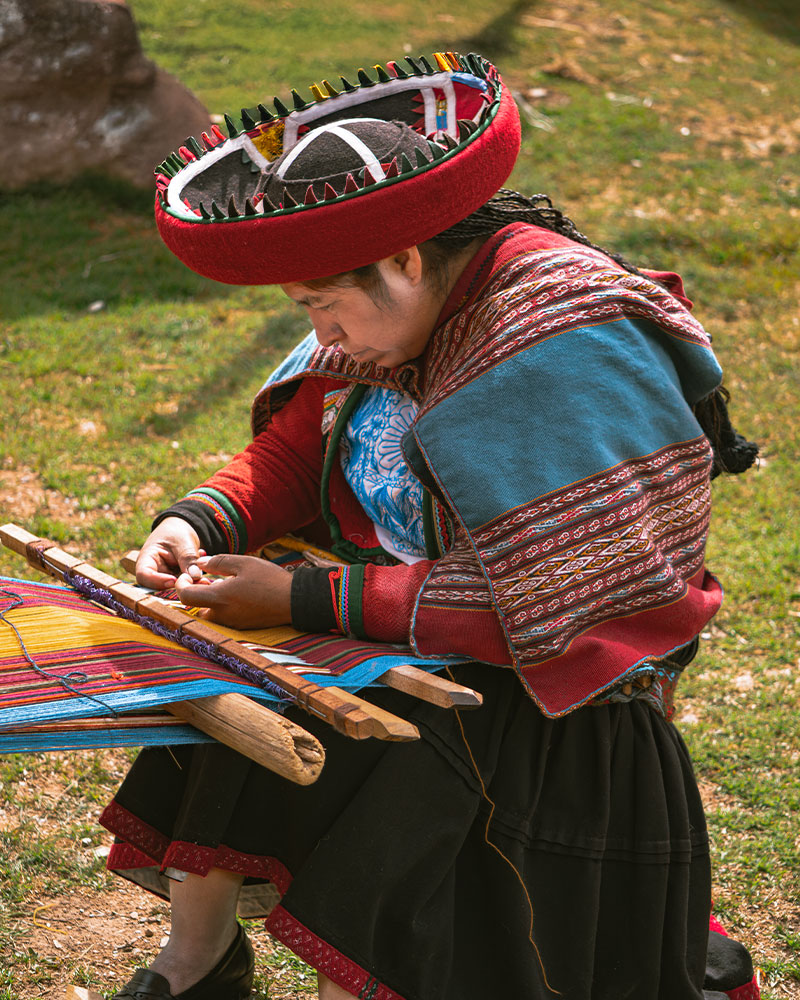 Woman weaving in Chinchero wearing traditional dress and using the famous backstrap loom
