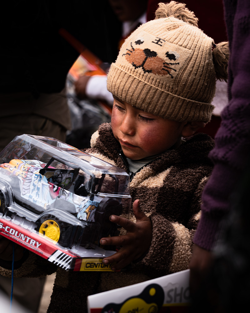 Child receiving a toy at Christmas thanks to the charity chocolate party organized by Salkantay Trekking in the community of Rodeana, Ocongate district.