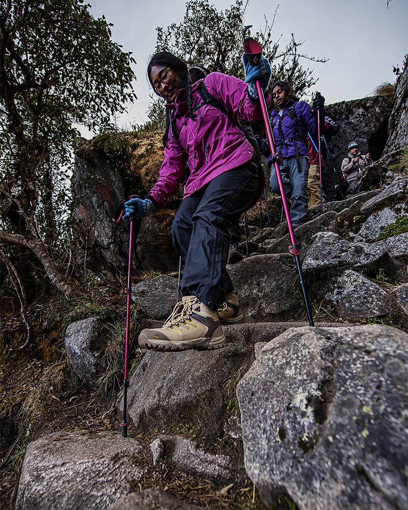 Tourists descending Inca steps in Machu Picchu with trekking poles