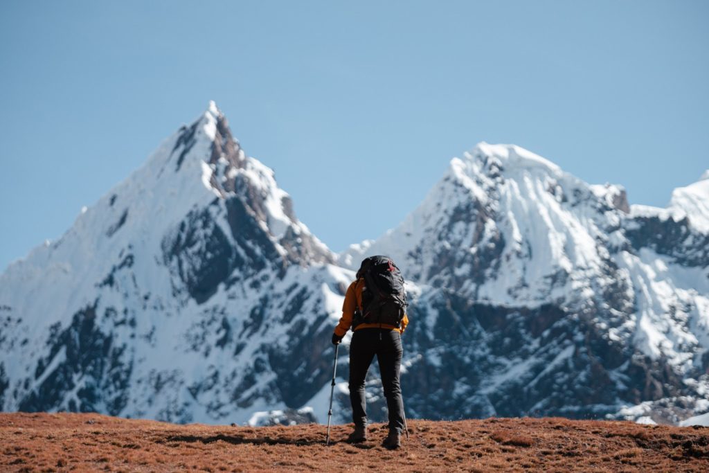Hiker in the Peruvian Andes surrounded by snow-capped mountains, experiencing a digital detox in nature