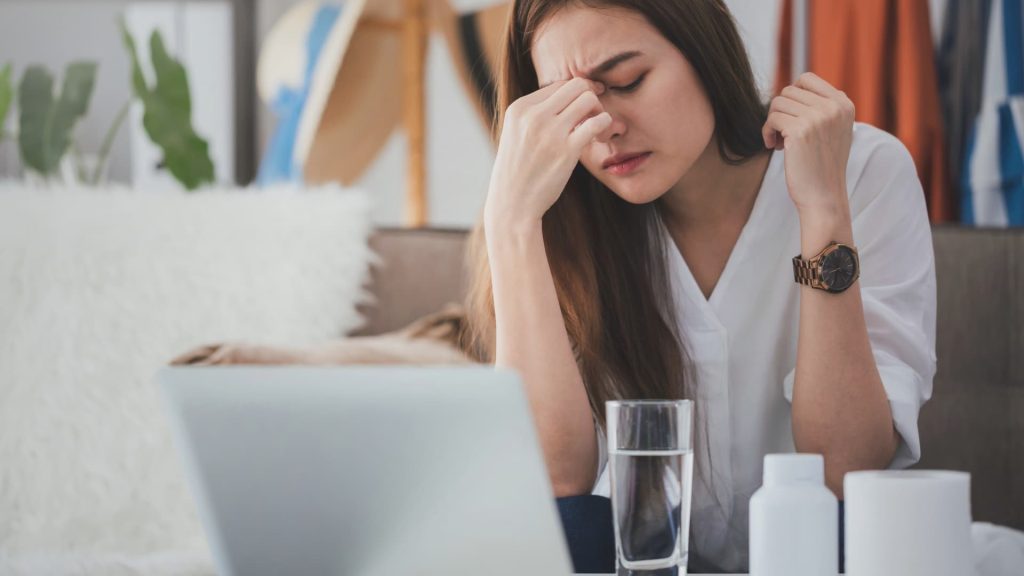 A person clutching their forehead with an expression of pain due to a severe headache.