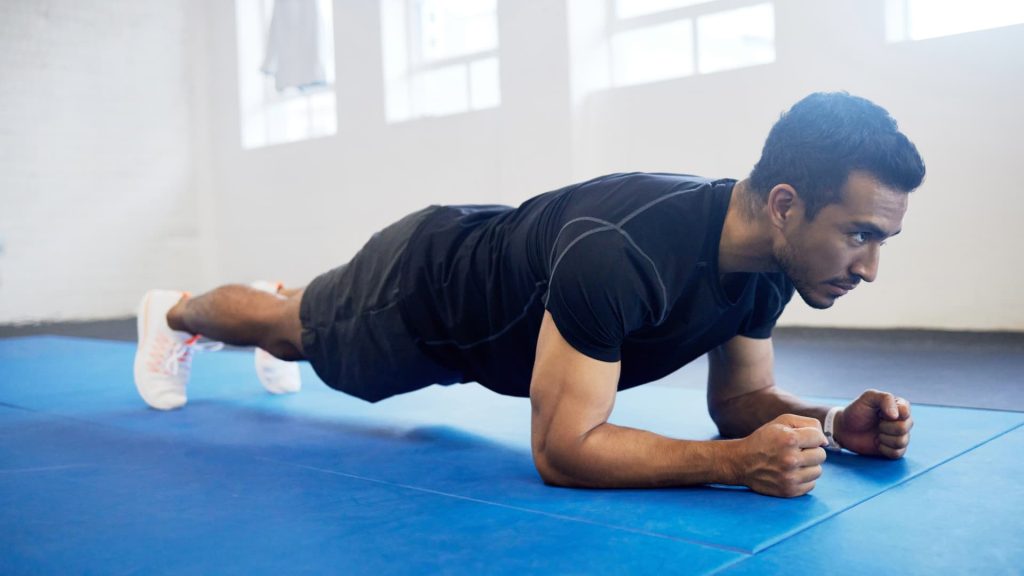 A person holding a forearm plank position on a blue mat during a core workout.