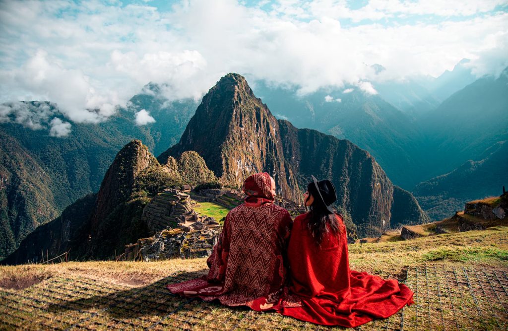 A tourist standing and looking out at the citadel of Machu Picchu from above.