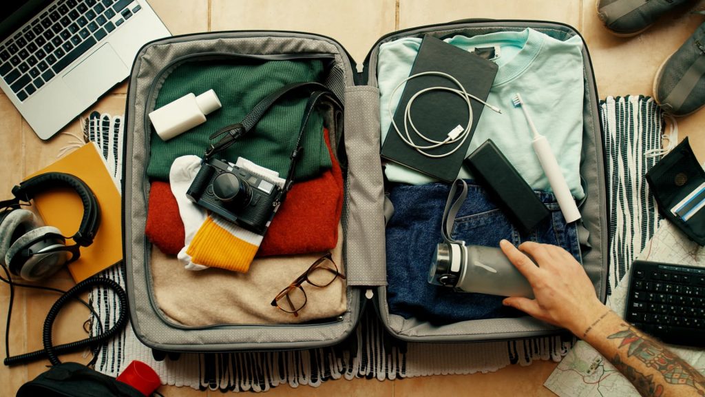 A traveler carefully organizing and packing clothes and gear into a hiking backpack.