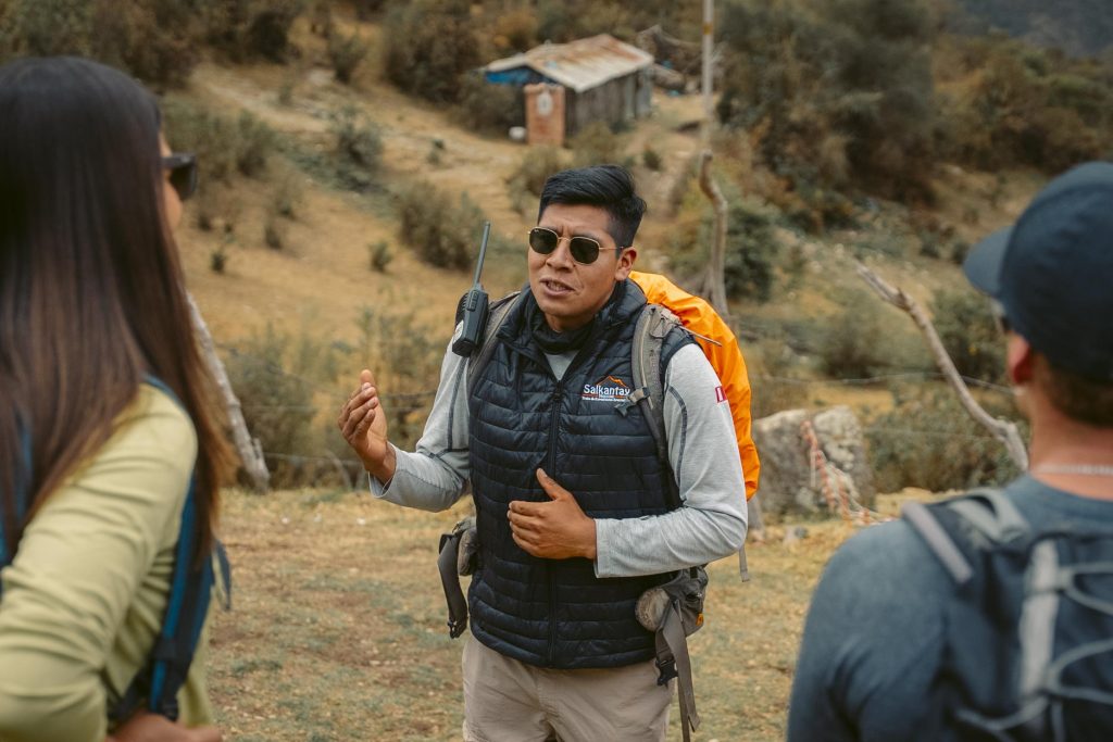 Tour guide explaining the Salkantay Trail hiking route to a group of tourists.