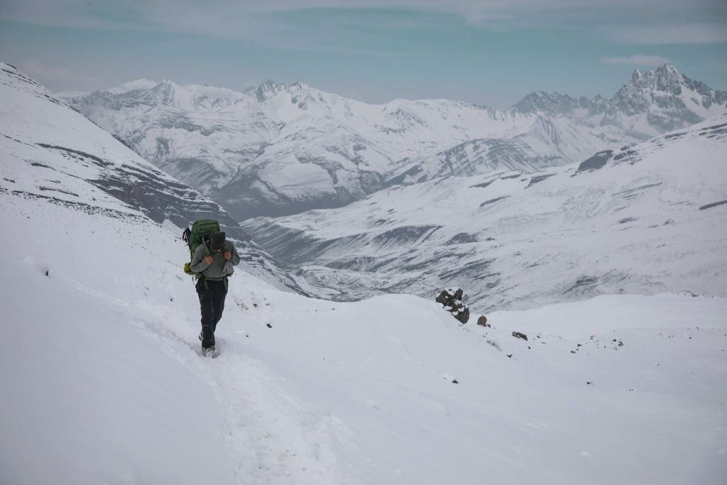 Tourist with hiking gear exploring the snow-capped Ausangate Mountains