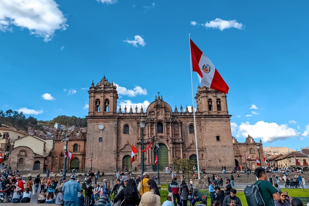 Cusco's main square filled with people waving a Peruvian flag