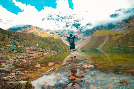 Person raising hands in front of Humantay mountain and lake