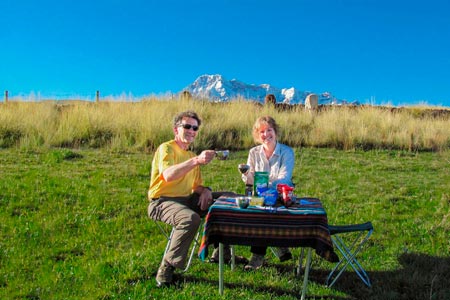 Two tourists enjoying a meal at the foot of the snowy