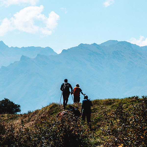Three tourists walking in the green mountains with breathtaking background of Andean mountains