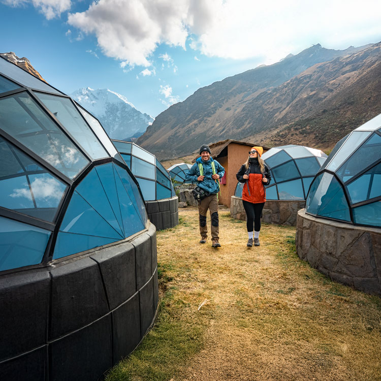 A young couple enjoying the incredible views from the Sky Camp glass igloos, surrounded by the dramatic mountain landscape of the Peruvian Andes.