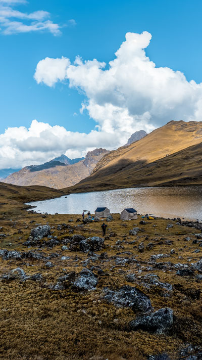 Panoramic view of a campsite next to a lagoon in the Andean mountains of Lares in Peru