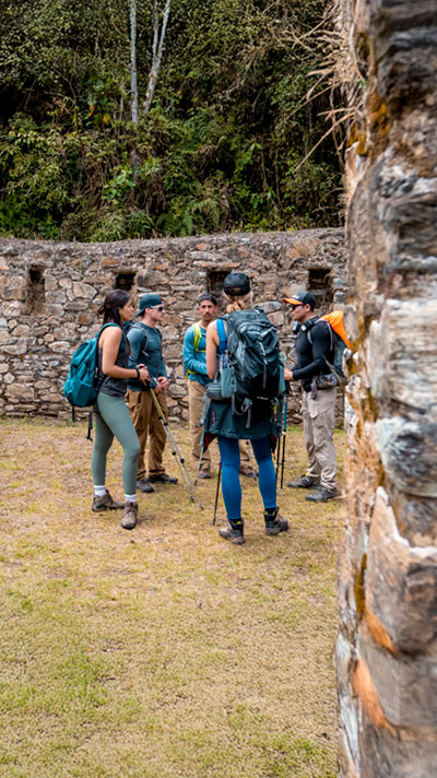 Group of travelers in Peru visiting the Llactapata Archaeological Inca Site surrounded by lots of vegetation during the Inca Jungle journey