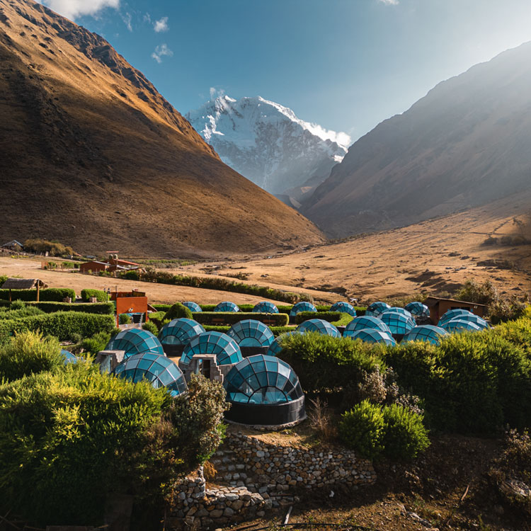 A breathtaking panoramic view of Sky Camp in Soraypampa, showing the collection of glass igloos nestled at the base of the towering Andean mountains.