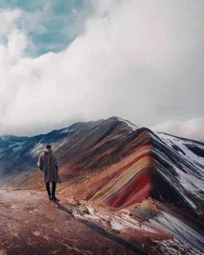 Spectacular photo of a tourist looking at the rainbow mountain