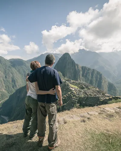 Tourist couple embraced enjoying an impressive view of Machu Picchu