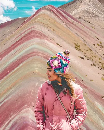 A photo of a tourist enjoying the wind of the Andes on the rainbow mountain