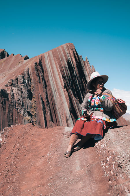 Andean woman sitting on Pallay Punchu