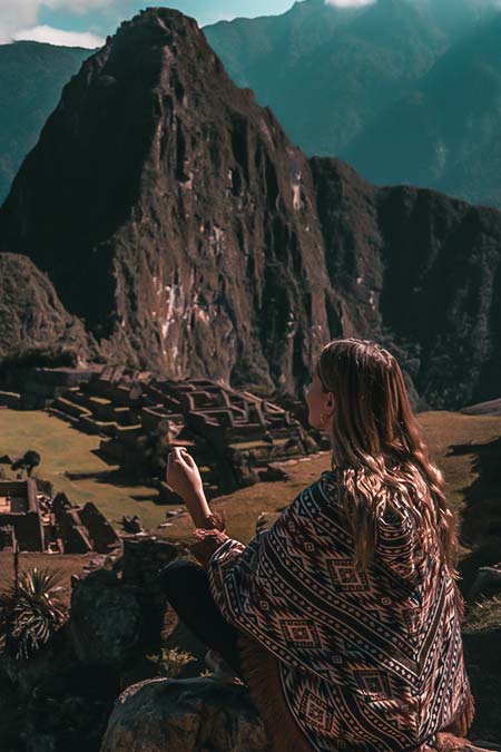 Tourists sitting with andean poncho in front of Machu Picchu