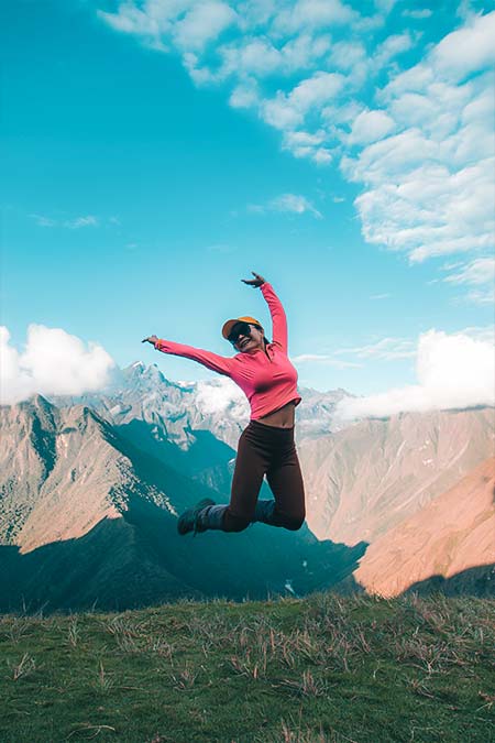 Female tourist jumping on the Inca Trail route to Machu Picchu