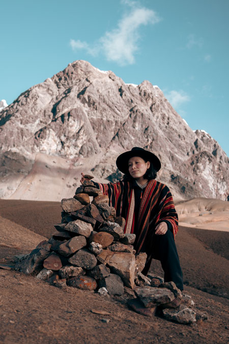 Female tourist next to a pile of stones called apacheta