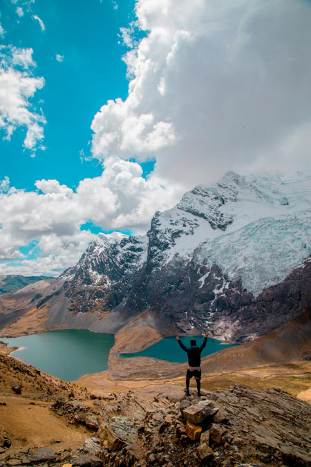 Tourist raising his hands in front of the sacred Ausangate mountain with its two deep lakes.