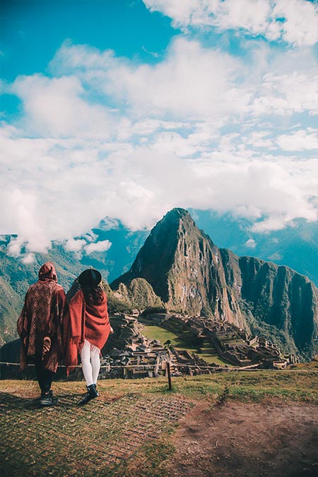 Tourists with red Andean poncho in Machu Picchu on a hot day