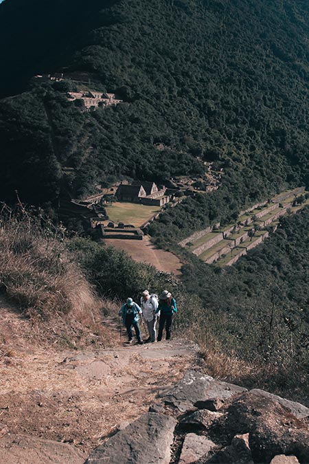 Tourists walking against the backdrop of the majestic Choquequirao archaeological site.