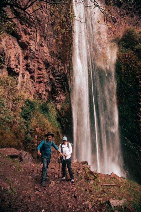 Two tourists posing for a photo next to the immense Perolniyoc waterfall.